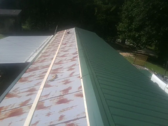 Old rusted panels beside newly installed green metal roofing — Wind Damage Roof Repair by Roofing Brothers in De Soto
